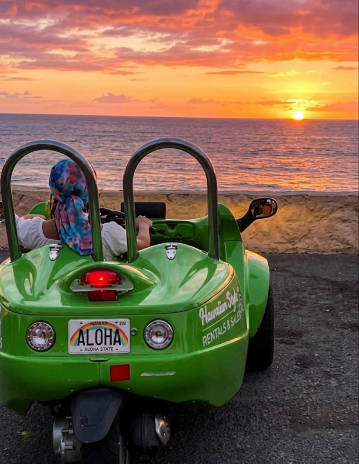 Green 3 wheel car parked near a Hawaii sunset